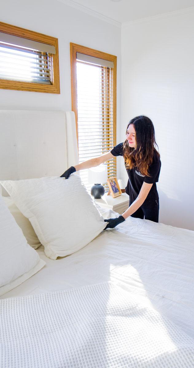 Fresh white bed linen being smoothed flat